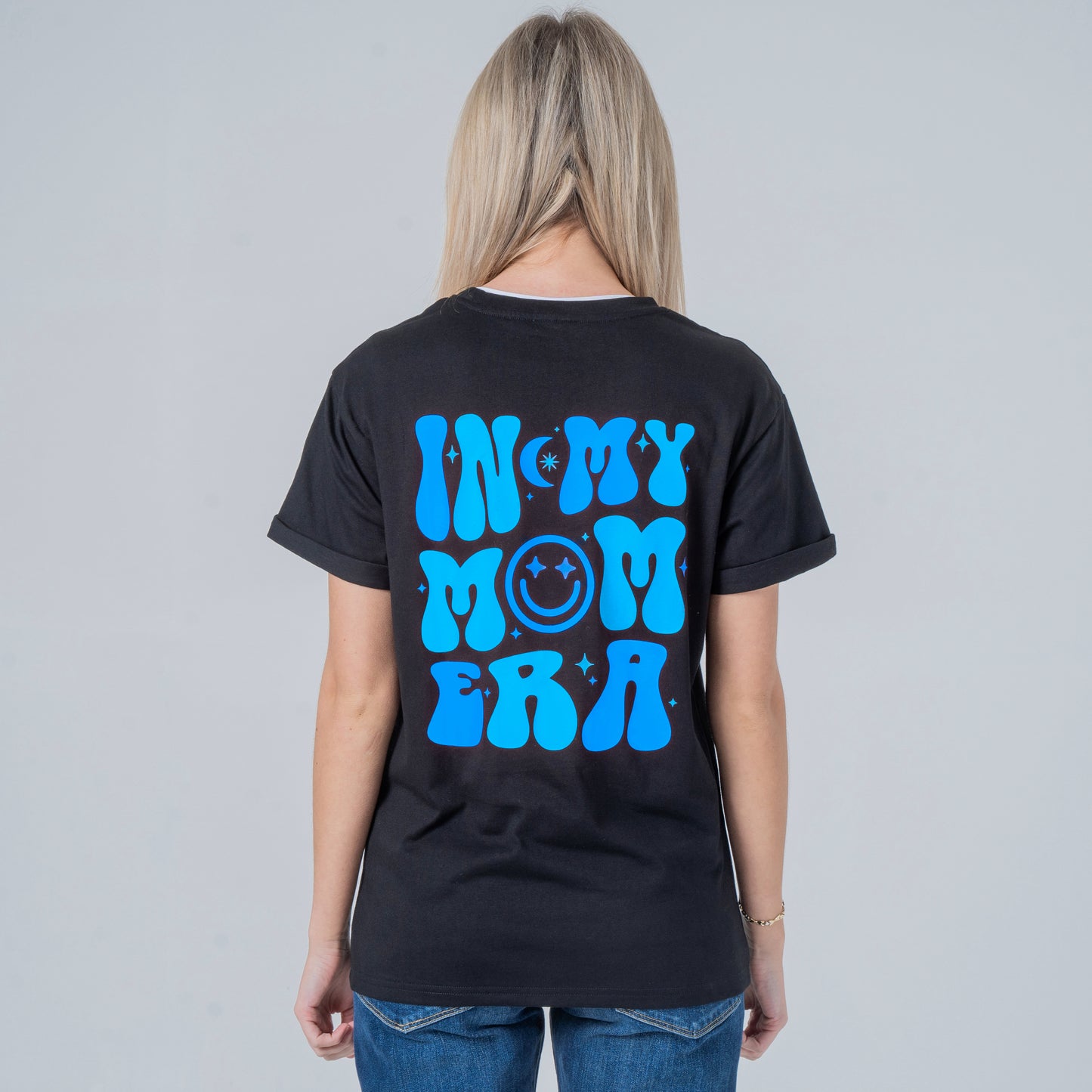 Woman wearing a black t-shirt with blue graphic on the back against a gray background