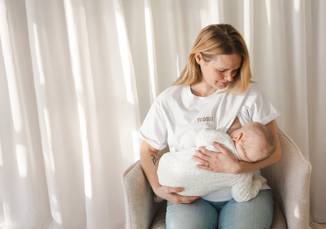 Smiling mom breastfeeding her baby in a white Milkmates nursing tee and jeans