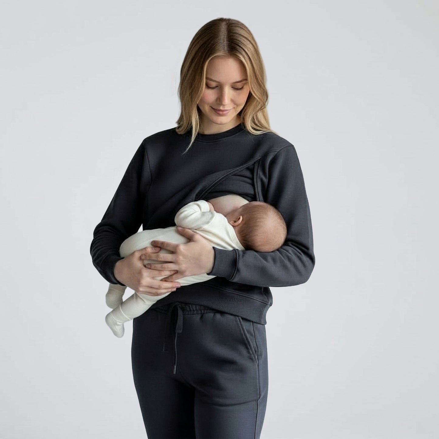 Woman wearing milkmates nursing sweater and sweatpants set - feeding baby