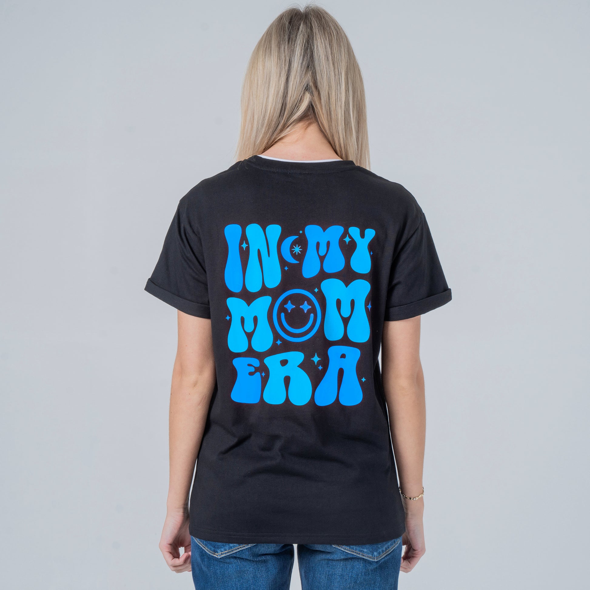 Woman wearing a black t-shirt with blue graphic on the back against a gray background